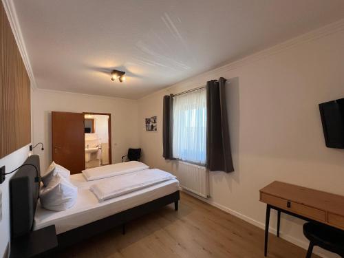 a bedroom with a bed and a desk and a window at Hotel Bastei in Mühldorf