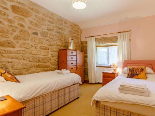 a bedroom with two beds and a stone wall at 2 Bed in Bodmin oc-chest in Lanlivery