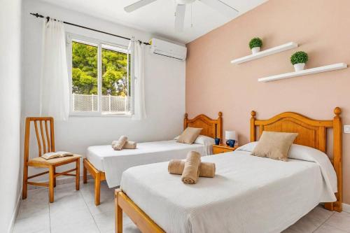 a bedroom with two beds and a chair and a window at Villa Rincon by Villa Plus in Cala Blanca