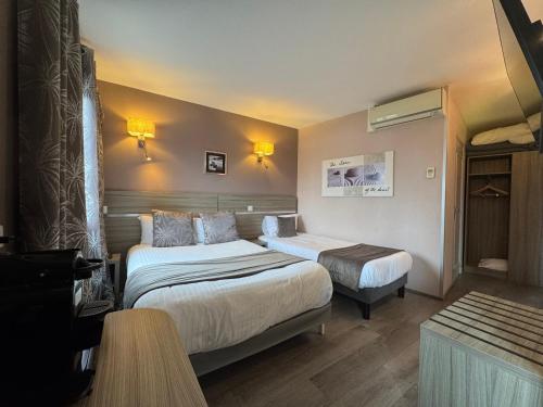 a hotel room with two beds and a table at Logis Hôtel Centrotel et Spa Bulles d'Allier in Montmarault