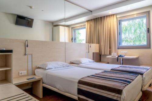 a hotel room with two beds and two windows at Park Hotel Porto Aeroporto in Maia