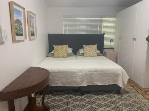 a bedroom with a large bed and a table at Just a Bed parking on street in Stellenbosch
