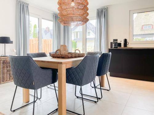 a dining room table with chairs and a chandelier at Hygge Hus 1 in Timmendorfer Strand