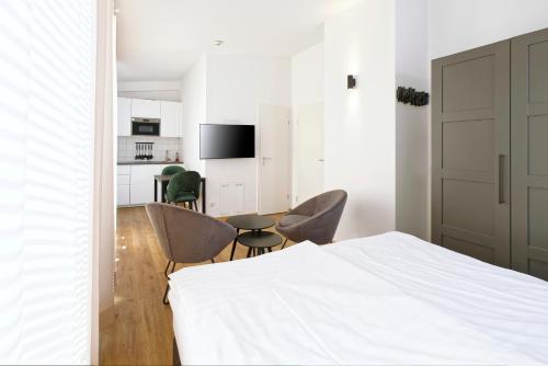a bedroom with a bed and chairs and a kitchen at Boardinghouse Rosenheim in Rosenheim