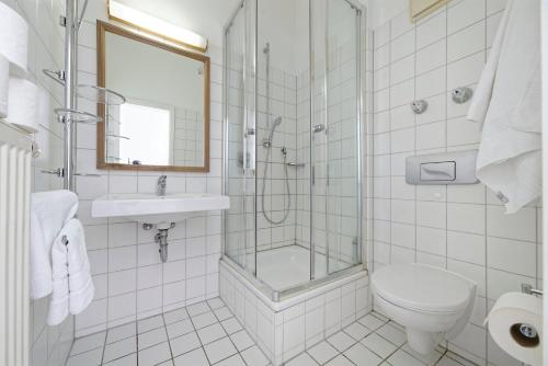 a white bathroom with a shower and a toilet and a sink at Boardinghouse Rosenheim in Rosenheim