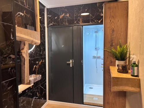 a bathroom with a shower with a black wall at Vinkenland in Koningslust