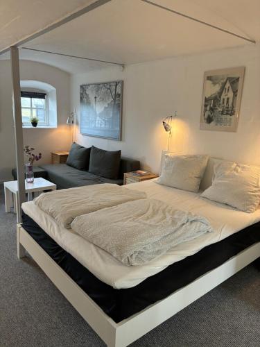 a bedroom with a large bed and a couch at Klitgaards Holiday Apartment in Mejeriby