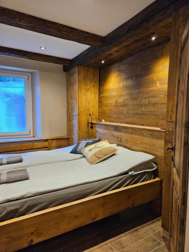 a large bed in a room with a wooden wall at Alleghe Lodge in Masarè