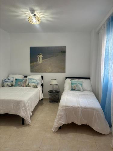 a bedroom with two beds and a painting on the wall at Apartamento Amy 4 in Huelva
