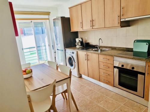 a kitchen with a wooden table and a dining room at Apartamento Montegordo in Monte Gordo