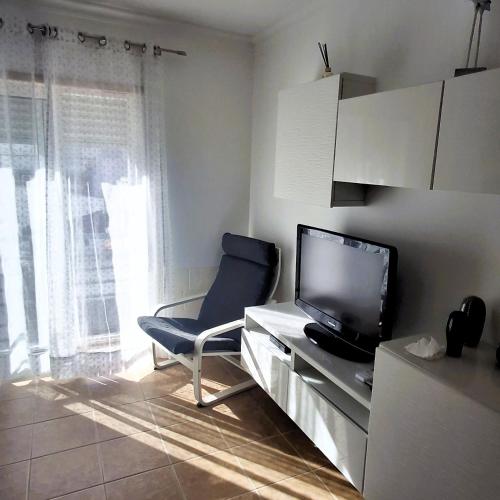 a living room with a tv and a blue chair at Apartamento Montegordo in Monte Gordo