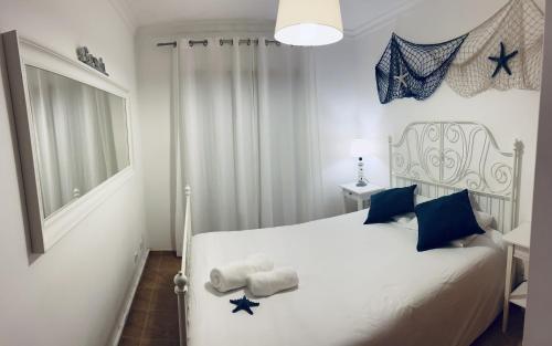 a bedroom with a white bed with blue pillows at Apartamento Montegordo in Monte Gordo