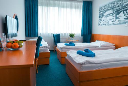 a hotel room with three beds and a desk at Hotel Ledňáček in Ostrava
