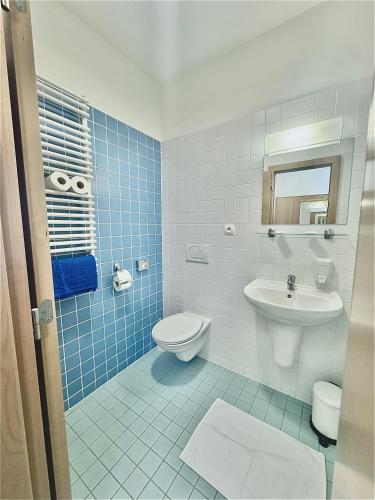a blue tiled bathroom with a toilet and a sink at Hotel Ledňáček in Ostrava