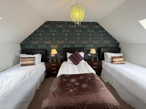 a bedroom with two beds and a chandelier at Abalone Accommodation in Culbokie