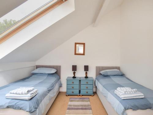two twin beds in a attic bedroom with a window at 3 Bed in Lostwithiel oc-93041 in Lostwithiel