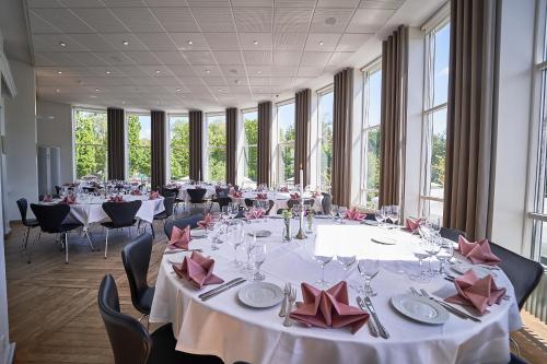 a large room with tables and chairs and windows at Vejlsøhus Hotel and Conference Center in Silkeborg