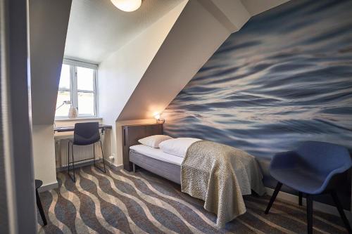 a bedroom with a painting of the ocean on the wall at Vejlsøhus Hotel and Conference Center in Silkeborg