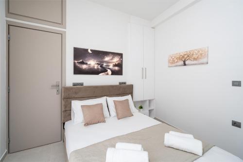 a white bedroom with a large white bed with pillows at Notos Horizon in Ierapetra