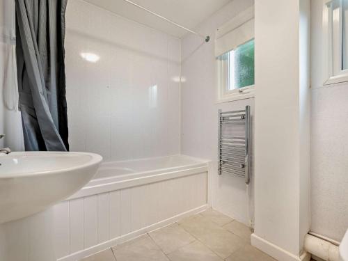 a white bathroom with a sink and a bath tub at 3 Bed in Saltash oc-30040 in Wotter