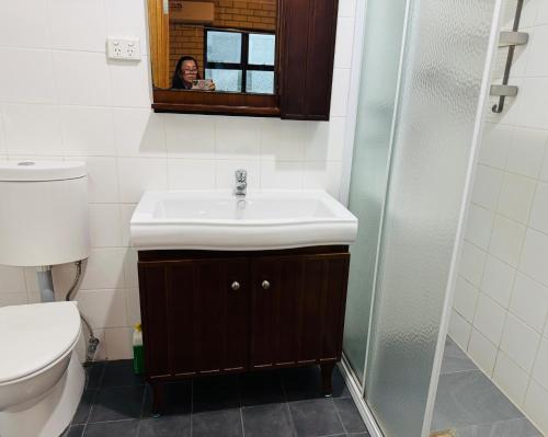 a woman taking a picture of a bathroom with a sink at Less pay for master room in Rosewater