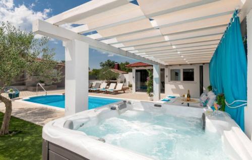 a hot tub in a backyard with an umbrella at Villa Korana with heated Pool & Jacuzzi in Kamenmost