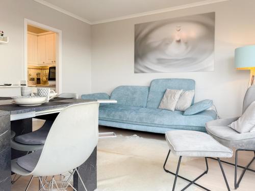a living room with a blue couch and chairs at Carpe Diem 203 in Niendorf