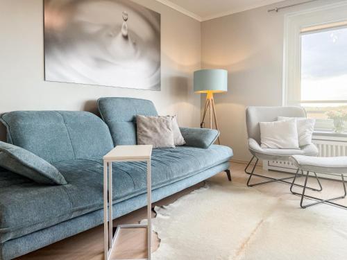 a living room with a blue couch and a chair at Carpe Diem 203 in Niendorf
