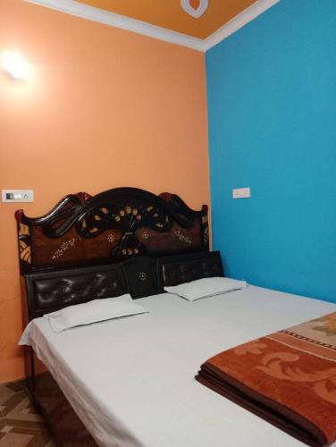a bedroom with a bed and a blue wall at Green Valley Homestay in Barkot