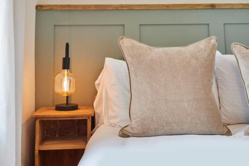 a bed with white pillows and a lamp on a table at Church View Cottage & Secret Garden, Matlock - Now Hosted by StayHostSave in Matlock