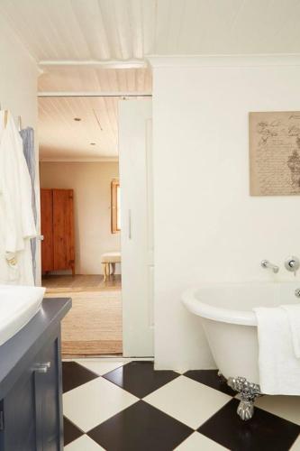 a bathroom with a white tub and black and white checkered floor at Vleidam Guest Farm in Koringberg