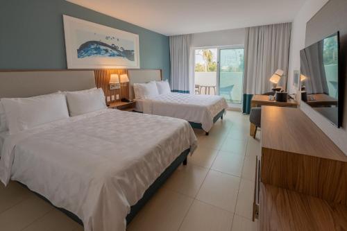 a hotel room with two beds and a television at Holiday Inn Acapulco La Isla by IHG in Acapulco