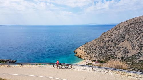 a person with two bikes on a road next to the ocean at Villa Ante - Private Pool, Wellness & Gym in Šestanovac