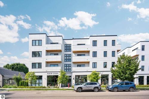two cars parked in front of a white building at 1 Block to Beach | Bikes, Wellness & More in Traverse City