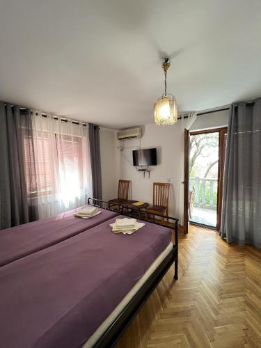 a bedroom with a large bed with a purple blanket at Rooms Villa Desa in Budva