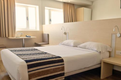 a bedroom with a large white bed and a mirror at Park Hotel Porto Gaia in Vila Nova de Gaia