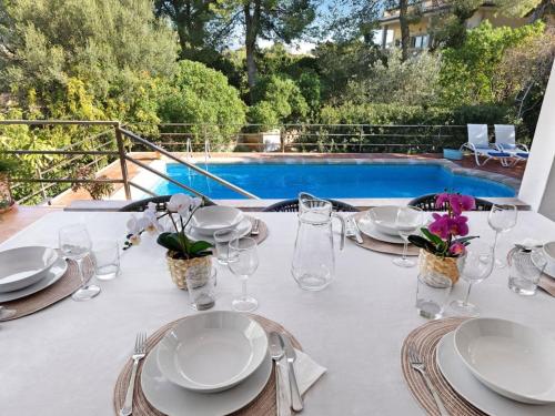 a white table with plates and glasses and a pool at Casa del Capitán in Santa Ponsa