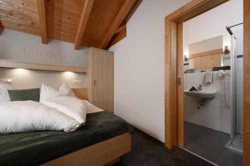 a bedroom with a bed and a bathroom with a sink at Apart Marie-Therese in Umhausen
