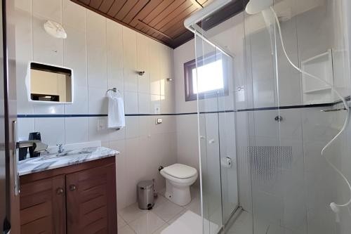 a bathroom with a toilet and a glass shower at Casa Morrinhos 17 in Garopaba