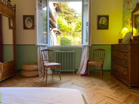 a bedroom with a bed and two chairs and a window at La Villa Rose in Blaye