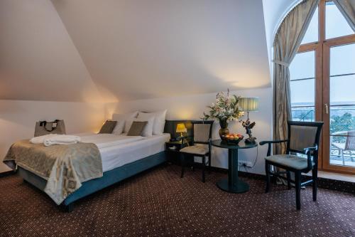 a bedroom with a bed and a table and a window at Darovanský Dvůr - Wellness & Golf Hotel in Břasy