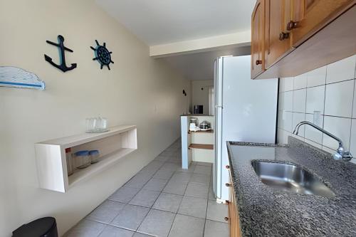 a kitchen with a sink and a refrigerator at Condomínio Villa do Oceano in Garopaba