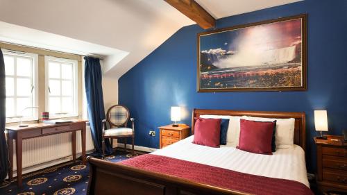 a bedroom with a bed with a painting on the wall at Santo's Higham Farm Hotel in Alfreton