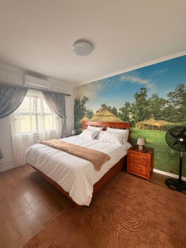 a bedroom with a large bed with a painting on the wall at Demmys Comfort in Cape Town