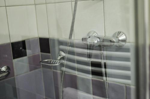 a shower with a shower head in a bathroom at Páva Apartmanház in Makó