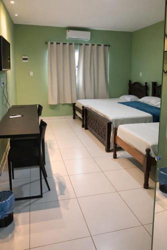 a bedroom with two beds and a desk and a table at Pousada Madre De Deus in Brejo da Madre de Deus