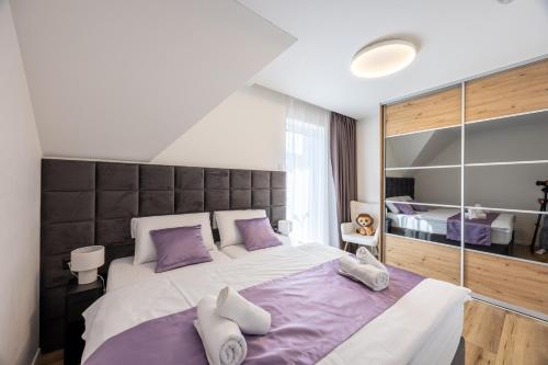 a bedroom with a large bed with purple pillows at Villa Lilien Residence Tatry in Veľká Lomnica