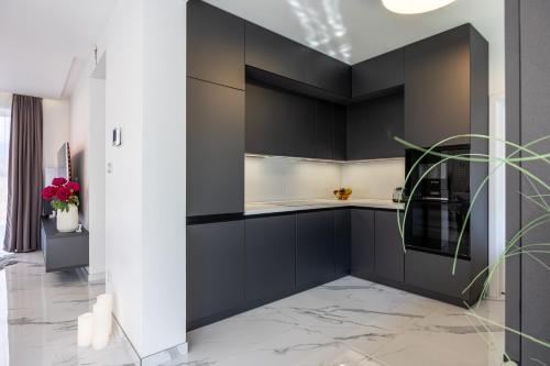 a kitchen with black cabinets and marble flooring at Villa Lilien Residence Tatry in Veľká Lomnica