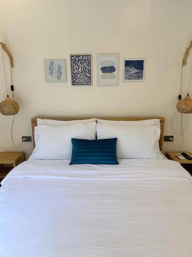 a white bed with a blue pillow on it at The San Juan House in san juan la union