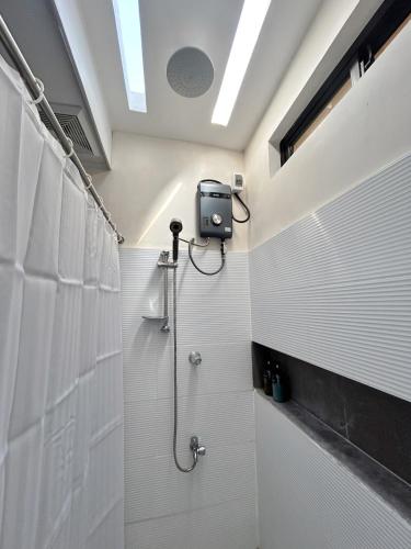 a bathroom with a shower with white tiles at The San Juan House in san juan la union